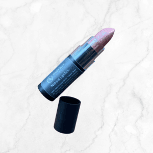 A tube of pale pink lipstick with a black label rests on white marble next to its cap, revealing the shade inside—ideally complemented by Flawless Glow Blush for a luminous look.