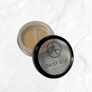 A round container of Aspen Foundation loose powder with a clear lid showing the brand logo rests on white marble; the powder inside is lightly tan.