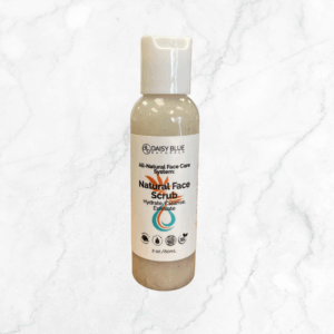 A 2 oz (60 mL) bottle of Natural Face Scrub with a flip-top cap rests on white marble. The label features its hydrating, cleansing, and exfoliating benefits.