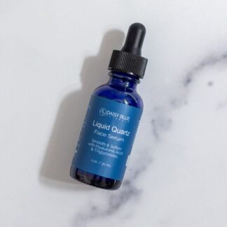 A blue dropper bottle of Liquid Quartz Face Serum sits on white marble, with a "BEST SELLER" tag in the top left corner. Experience the radiance of Liquid Quartz Face Serum today.